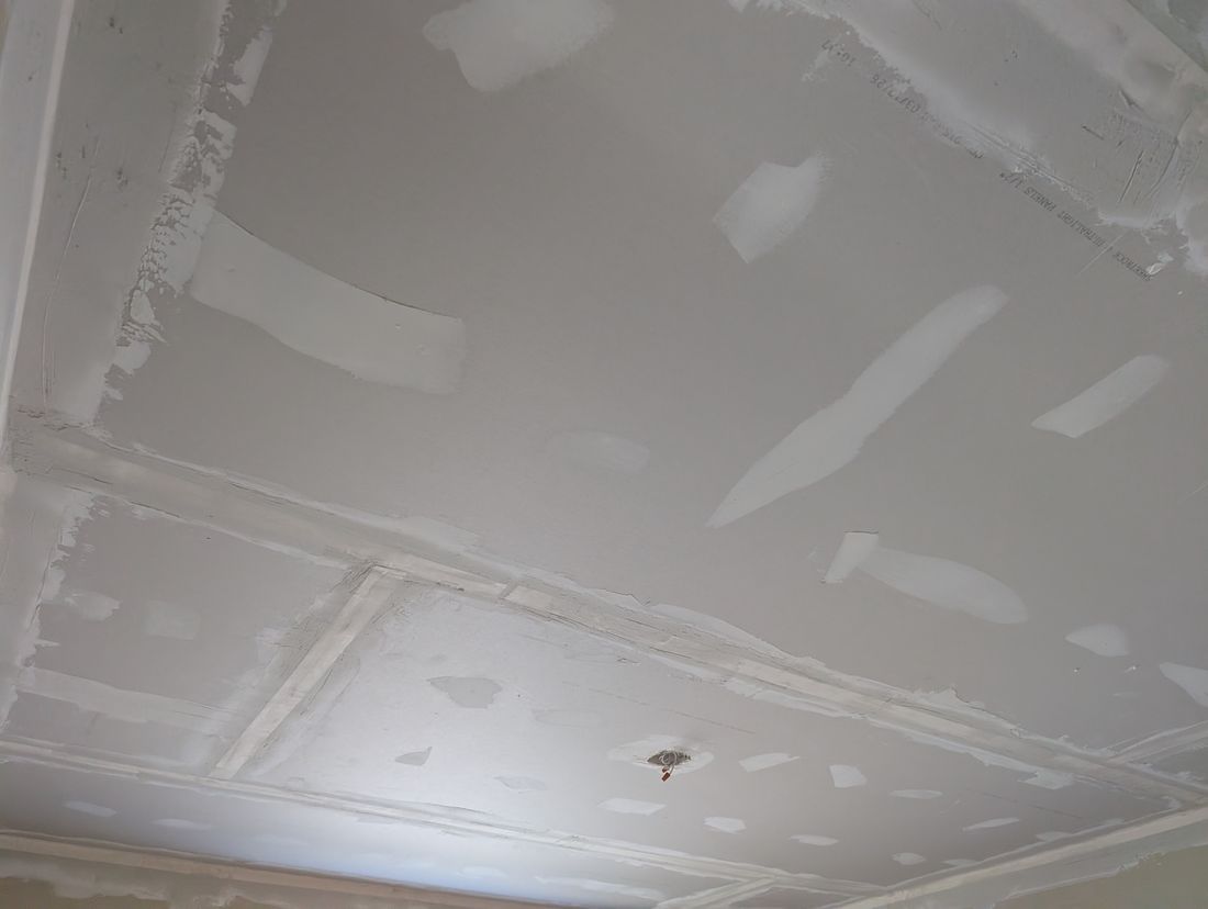 The same ceiling boarded, taped, with the first coat of compound on the seams.