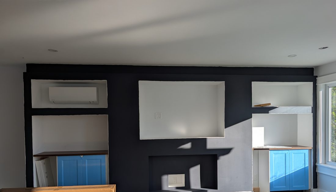 A living room with a deep navy painted feature wall and a white fireplace surround.